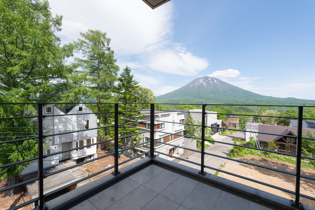 View of Mount Yotei covered in luscious green trees as seen from the balcony of Shinka in Niseko.