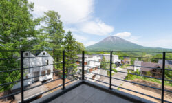 View of Mount Yotei covered in luscious green trees as seen from the balcony of Shinka in Niseko.
