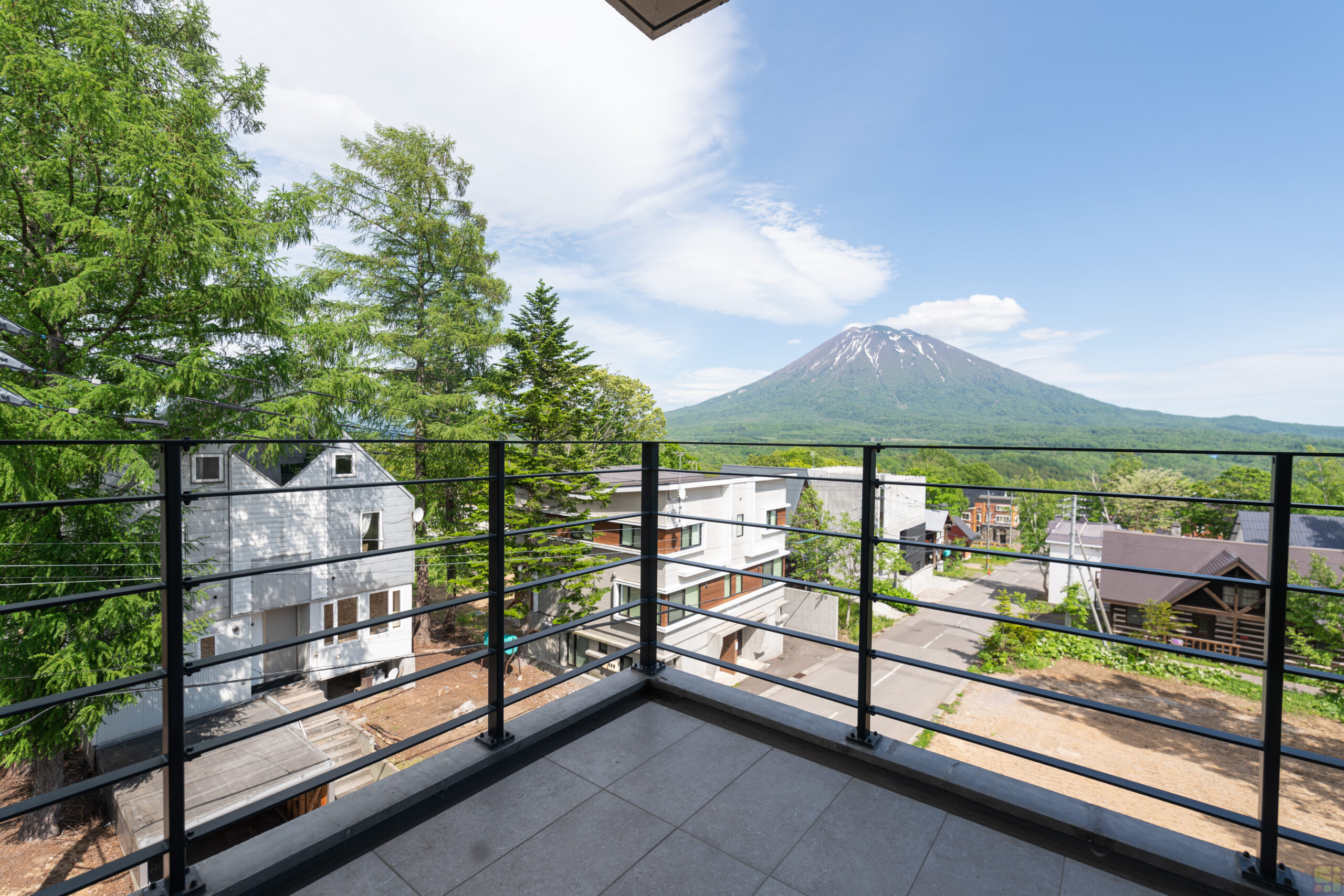 View of Mount Yotei covered in luscious green trees as seen from the balcony of Shinka in Niseko.